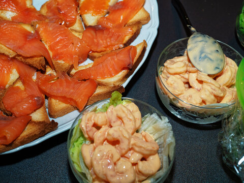 Dinner time on Christmas Eve with the family. Shrimp in pink sauce in two crystal glasses and toast with salmon served as an appetizer.