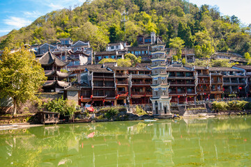 the river, the boat, stone bridge and the old houses at ancient phoenix town in the morning at...