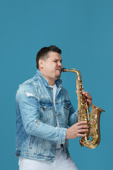 Fototapeta na wymiar handsome musician playing the saxophone in the studio blue background. Music concept.