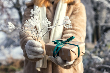Woman holding christmas present in snowy landscape. Small gift box in female hands	