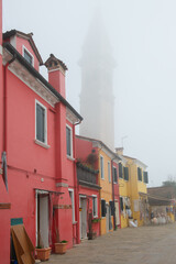 Fototapeta na wymiar Misty picture of street with colored houses in fog, italian island Burano, province of Venice, Italy, foggy weather.