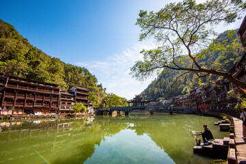 the river, the boat, stone bridge and the old houses at ancient phoenix town in the morning at...