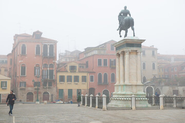 Fototapeta na wymiar Ancient beautiful square with an equestrian statue and buildings in Venice, Italy, foggy weather. Splendid medieval architecture, detail.