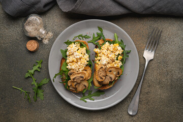 Morning breakfast sandwich with scrambled eggs and mushrooms. Nutritious snack in plate, top view