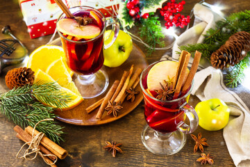 Mulled wine in glass mug with spices on rustic table. Winter Christmas hot drink with orange, apple and spices.