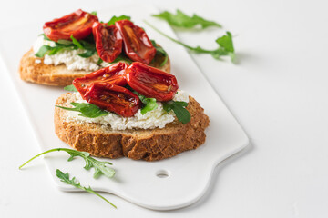 Bruschetta with sun dried tomatoes and arugula. Delicious breakfast or wine snack. White...