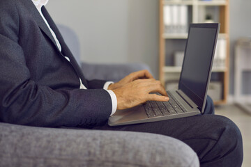 Businessman typing on laptop keyboard, entering data into database or doing marketing research