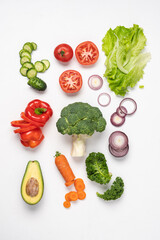 Creative layout made of variety of vegetables for making salads. Carrots, lettuce, kale, tomato, cucumber, broccoli, avocado, red bell pepper, onion.  White background, top view, copy space