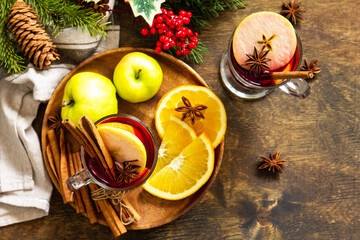 Winter Christmas hot drink with orange, apple and spices. Mulled wine in glass mug with spices on rustic table. Top view flat lay. Copy space.