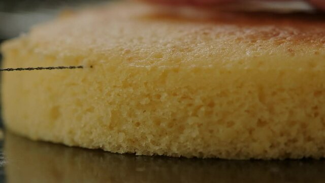 Close-up of cutting the top off a sponge cake to make a flat layer.