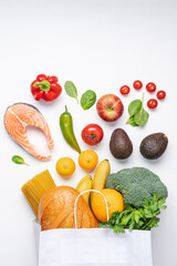 Healthy food  background. Vegetables, fruits, bread, pasta and salmon in paper bag. Variety balanced of healthy food products on white background