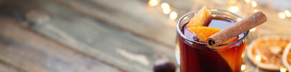 Traditional winter hot drink: mulled wine in glass decorated with orange, spices. Cozy atmosphere,...