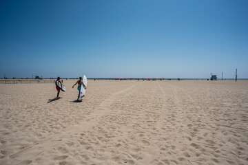 Couple on their way to surf in Santa Monica Beach, Los Angeles, California, USA