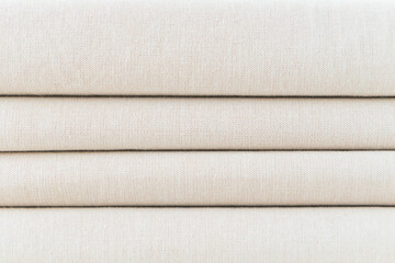 Stack of folded beige woven fabric patterned background