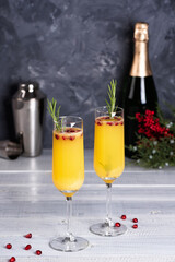 Mimosa coctail with orange juce and champagne. New Year or Birthday party. Pomegranate and rosemary