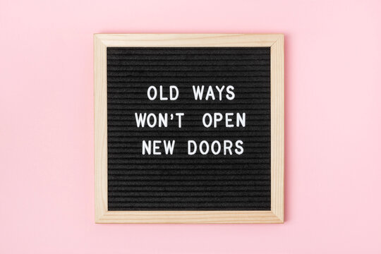 Naklejki Old Ways Won't Open New Doors. Motivational quote on black letter board on pink background. Concept inspirational quote of the day. Greeting card, postcard