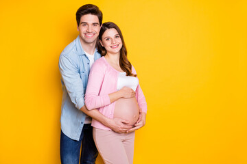 Photo of young couple stand hug pregnant woman wear casual outfits isolated on yellow color...