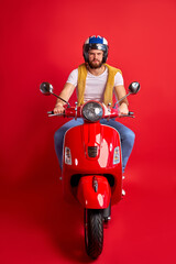 Fototapeta premium portrait of serious angry driver of motorcycle isolated over red studio background, young man in casual wear and helmet rushes