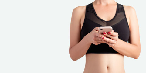 Online sport. Mobile app. Remote fitness. New normal. Unrecognizable athlete woman in black activewear bra using smartphone to track workout progress result isolated on white copy space background.