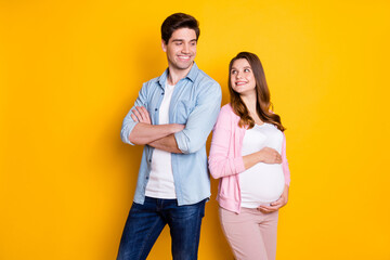 Photo of attractive pair expecting child father arms folded mommy hugging belly looking each other isolated yellow color background