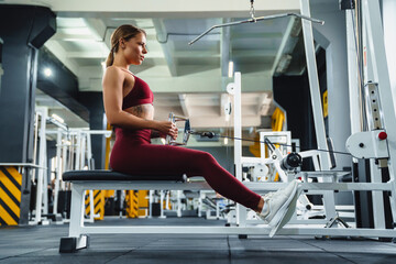 Sportswoman doing exercise on fitness equipment while working out