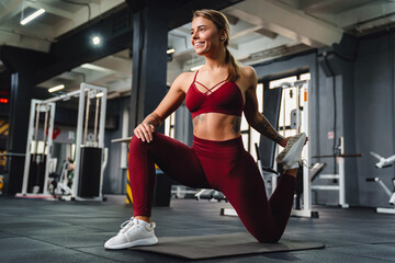 Smiling athletic sportswoman doing exercise on mat while working out