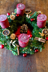 Adventskalender selbst gemacht. Rote Kerzen, Zimt, Kugeln, getrocknete Orangen, Tannenzapfen. Gold