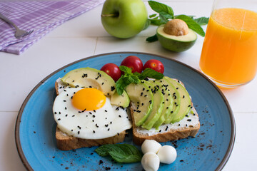 Healthy breakfast plate with cream cheese, avocado and eggs on dietary bread.