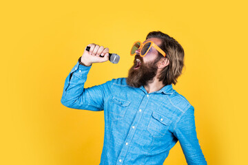 funny bearded brutal man with moustache wear party glasses and sing song in microphone, music