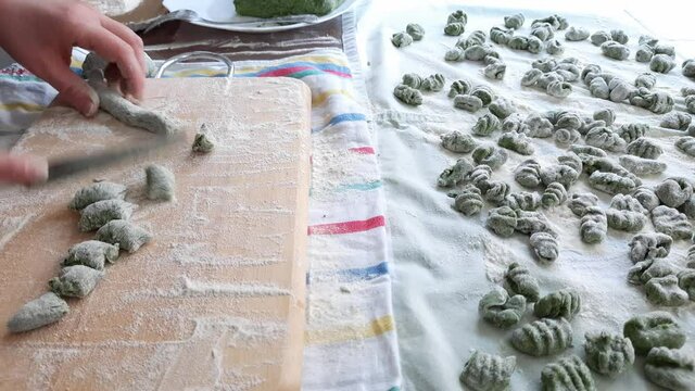 Real time video of female hands making raw spinach and potato gnocchi. Fresch green homemade italian dough dumplings on a towel.