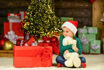 Fototapeta na wymiar Find presents online. happy new year. happy child santa hat. son ready to celebrate winter holidays. small boy excited with present. kid hold bear toy gift. toy shop is open at xmas. merry christmas