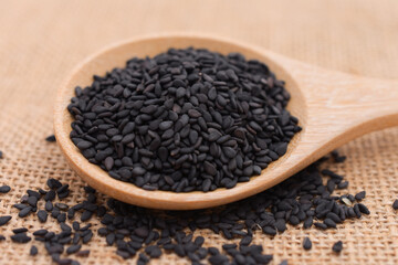 Black sesame seeds in wooden spoon.