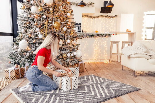 Young blonde woman going to unpack a giftbox with present