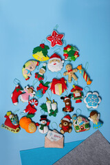 Handmade felt Christmas ornaments: elf, bear, nutcracker, snowman, santa claus are on a blue background. Concept of hand sewing, cute Christmas heroes, Christmas tree. 