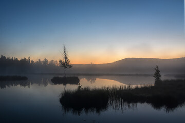 Fototapeta na wymiar Sunrise on czech moorland lakes with fog over the water