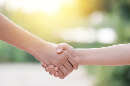 childs handshake on green spring background. shaking hand and sunshine in morning.
