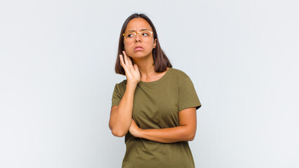 latin woman looking serious and curious, listening, trying to hear a secret conversation or gossip,...