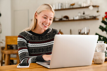 Smiling woman indoors at home using laptop