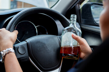 Drunk female driver with alcohol bottles sitting behind the wheel, not drinking and driving.