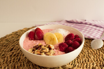 Presentation with banana, strawberry, raspberry, nut and coconut on fruit yogurt.