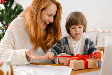 Mother and son opening present together while having Christmas lunch