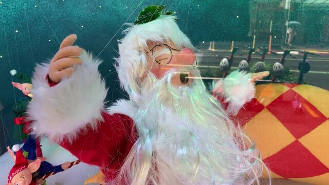 santa clause in the shopping window being postured by wire with glass merchandise elves