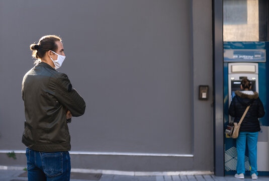 Young Man In Reusable Face Mask Waiting In Line At The ATM