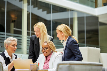 group of interracial business women listening to adult female boss, successful cooperation of colleagues, good work, they have conversation, in formal wear