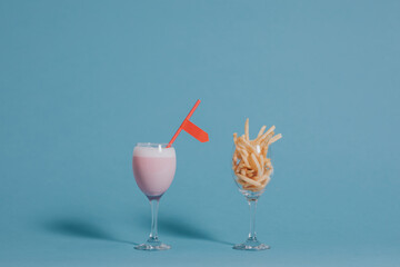 French fries in a wine glass beside a pink drink