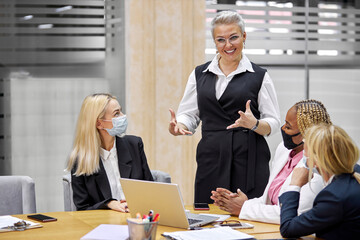 group of interracial business women listening to adult female boss, successful cooperation of colleagues, good work, they have conversation, in formal wear