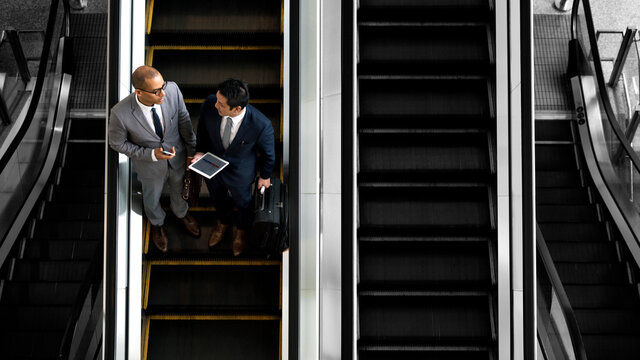 Business people discussing on an escalator - Powered by Adobe