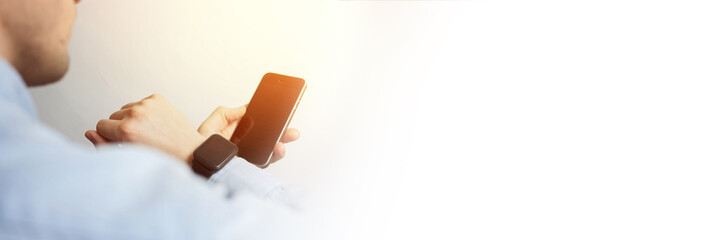 Side view, close-up of a smartphone with a blank screen and a smart watch on a male hand. Man using...