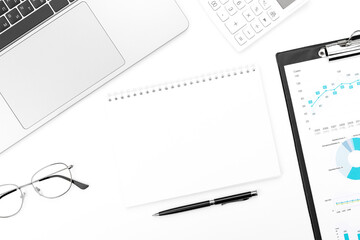 White page of notebook on office desk with laptop, glasses, calculator, pen and clipboard on white background. Flat lay, top view with copy space for your text.