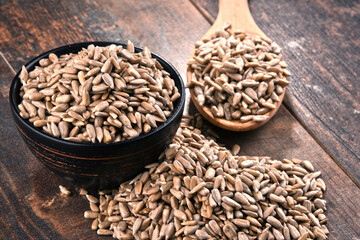 Composition with bowl of shelled sunflower seeds on wooden table
